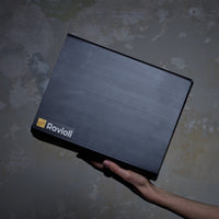 Foto einer schwarzen Ravioli-Verpackung von der Seite. Sie wird von einer Hand gehalten und das Ravioli Logo ist sichtbar.